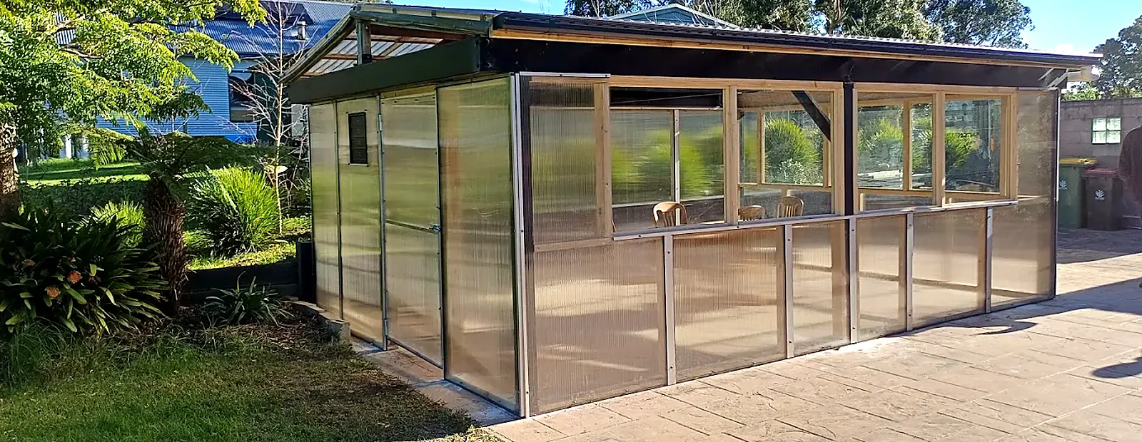 Timber-framed shed clad in polycarbonate sheeting on a paved area