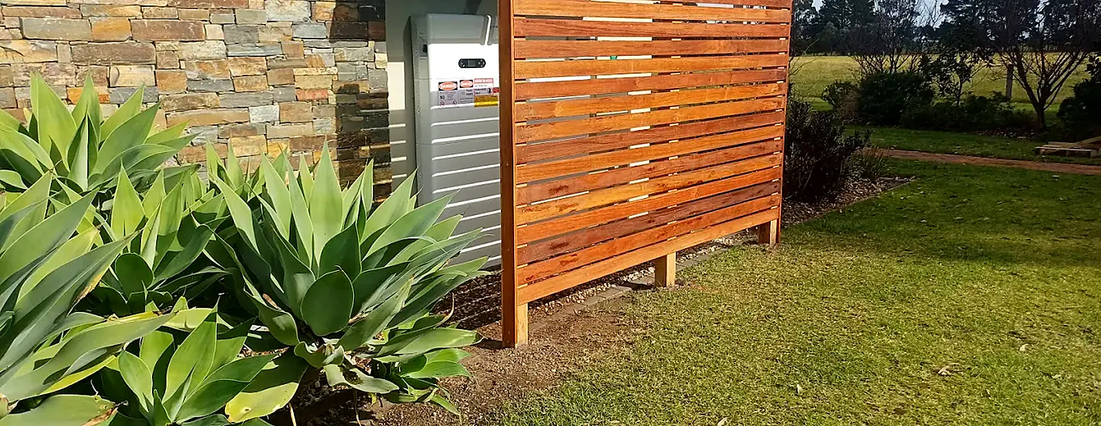 Horizontal timber slat privacy screen in front of a stone-clad wall