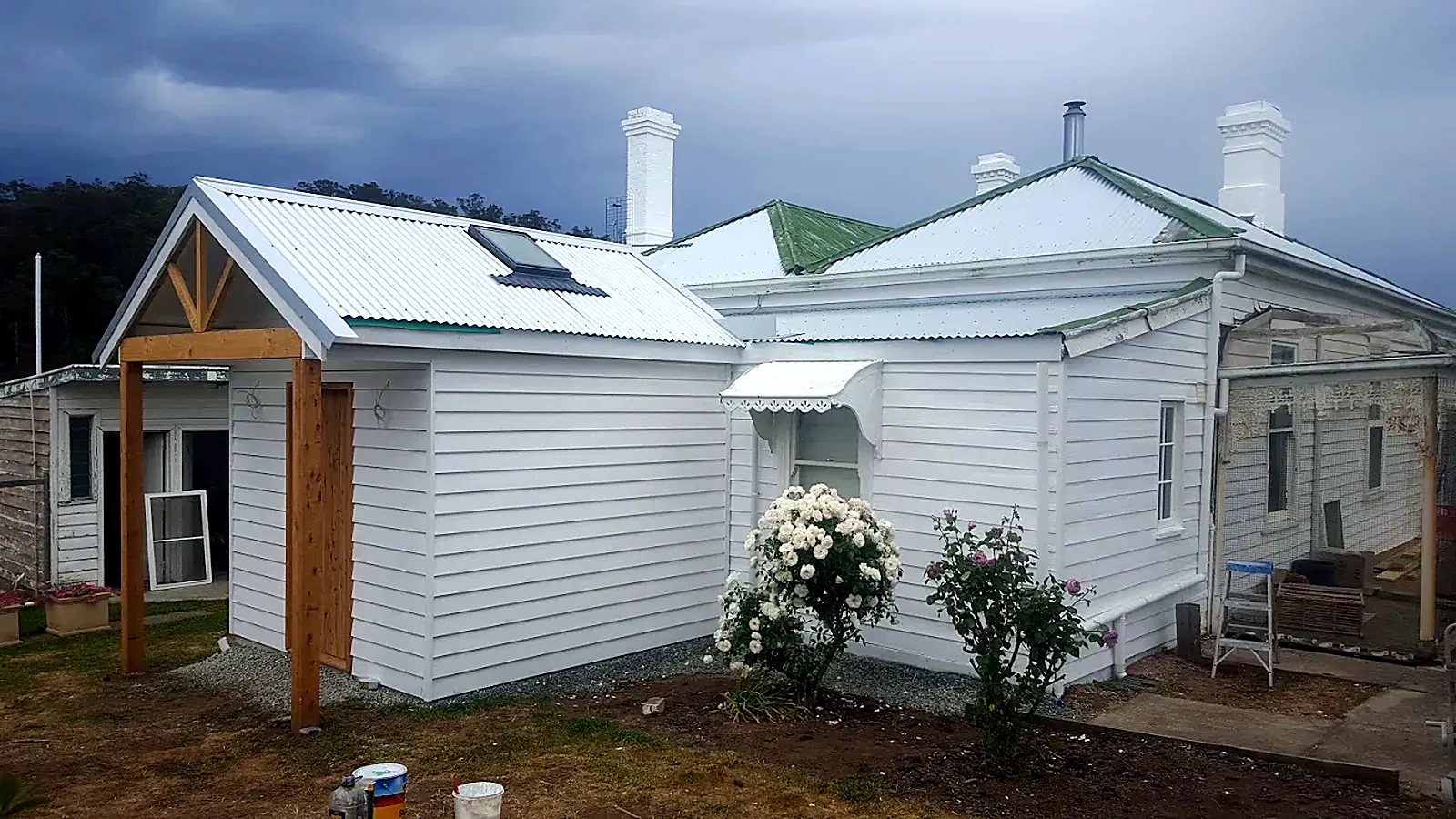 White weatherboard house with a new timber-framed porch and skylight roof
